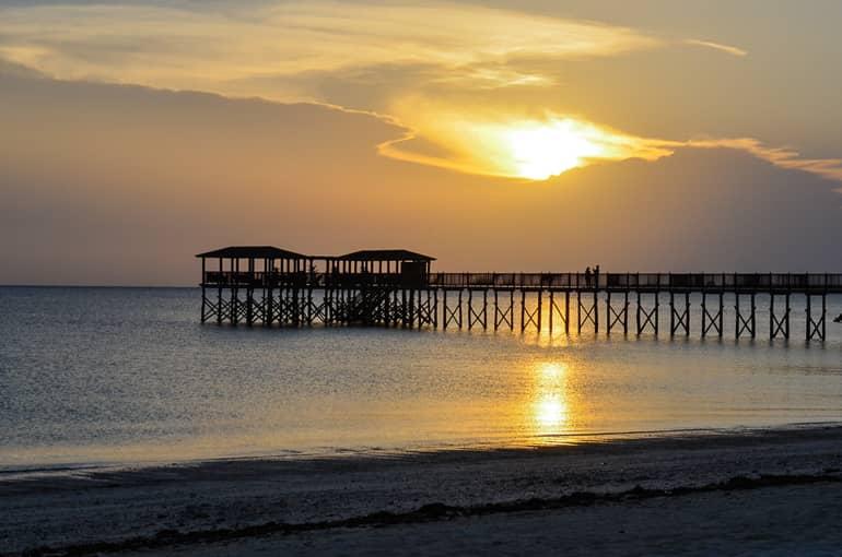 Puesta de sol en Zanzíbar, Tanzania, desde la playa de The Residence Zanzibar. Un muelle de madera conduce al mar.