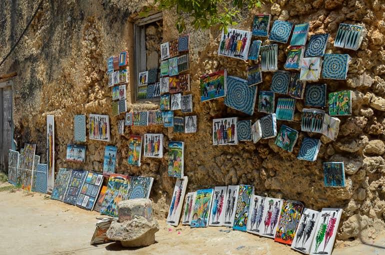 En una pared de piedra en Stone Town, Tanzania, se ofrecen obras de arte a la venta.