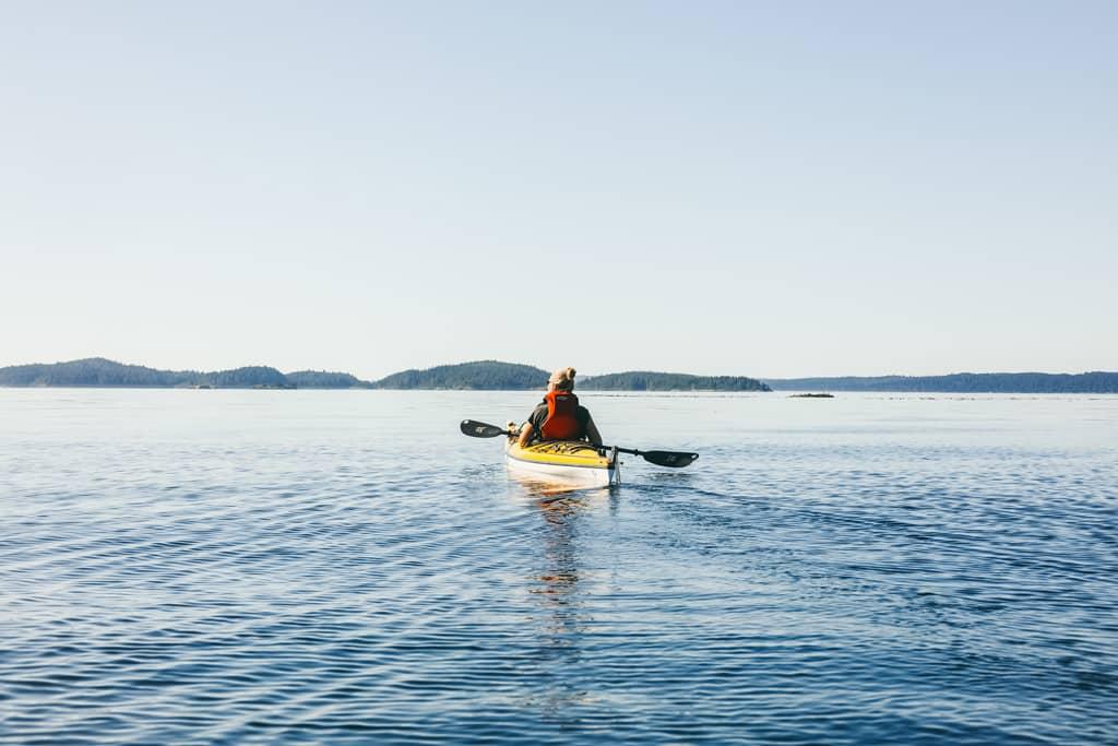 Kayaking Vancouver Island: A woman seen from behind in a kayak.