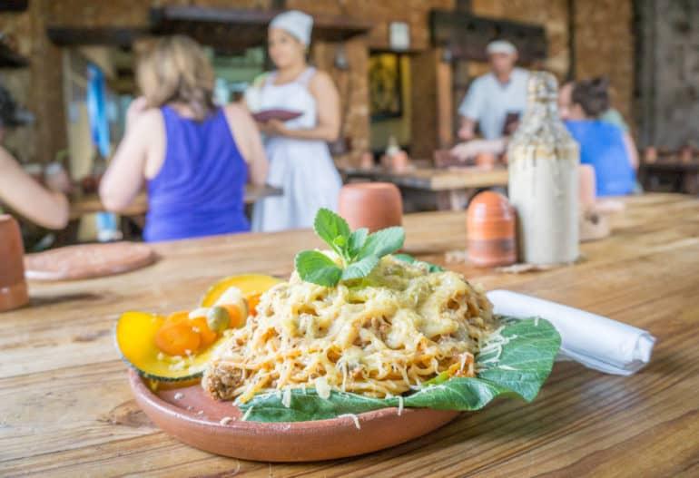 En la Taberna La Botija de Trinidad, se sirven espaguetis en platos terracota a los clientes en mesas de madera.