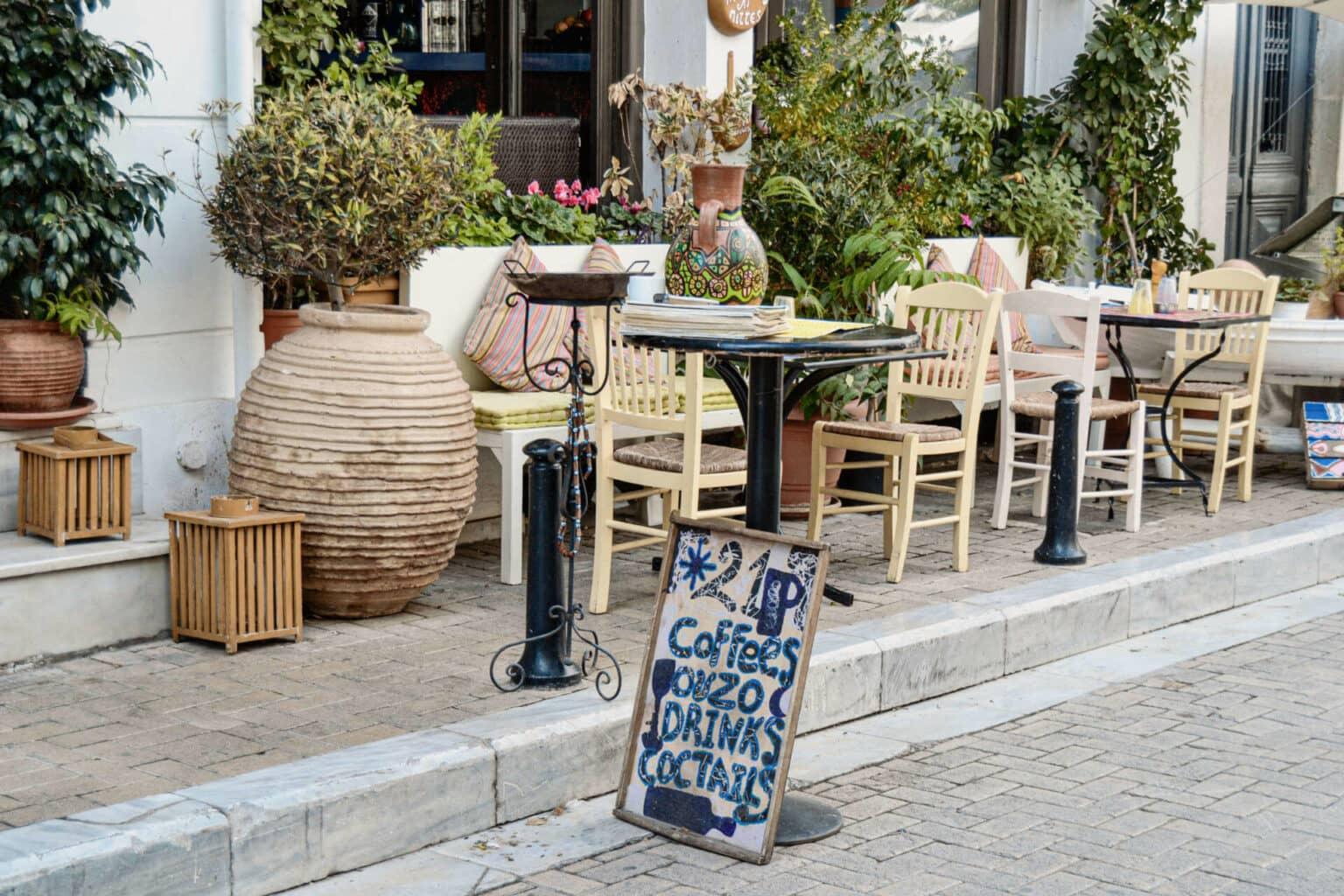 Outdoor terrace of a café in Athens in the Plaka district with inviting small chairs and tables.