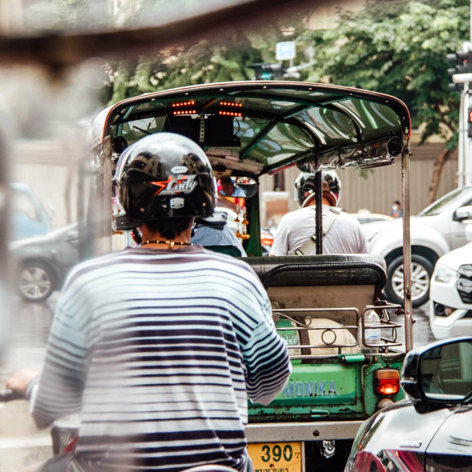 Tuk Tuks and locals on scooters weave through Bangkok's traffic.