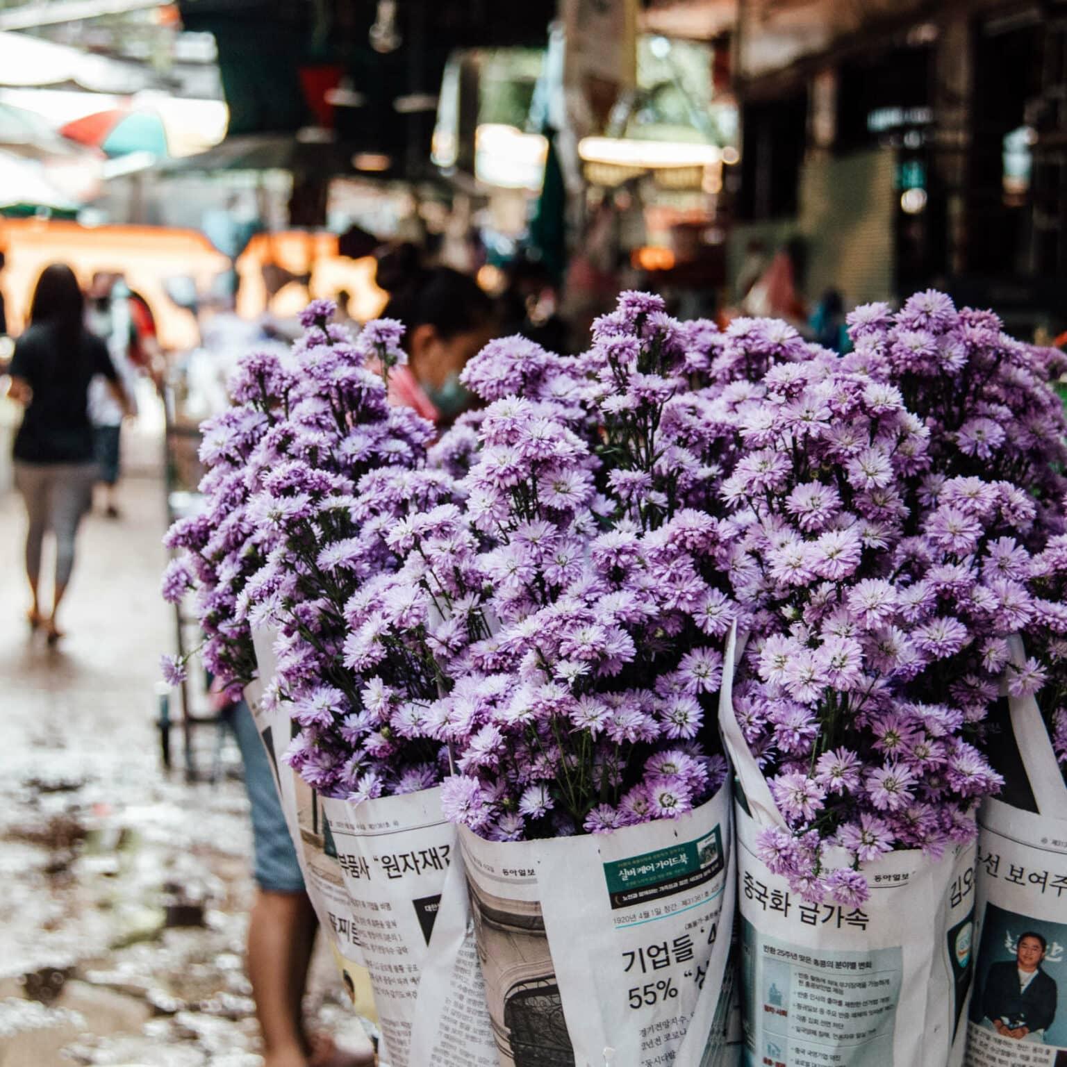 Purple flowers wrapped in newspaper at a market in Bangkok.