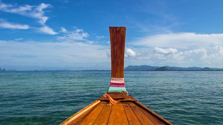 Un longtail boat en el camino a Koh Ngai se puede dejar llevar por los colores vibrantes del mar y disfrutar de la vista, como en una postal.