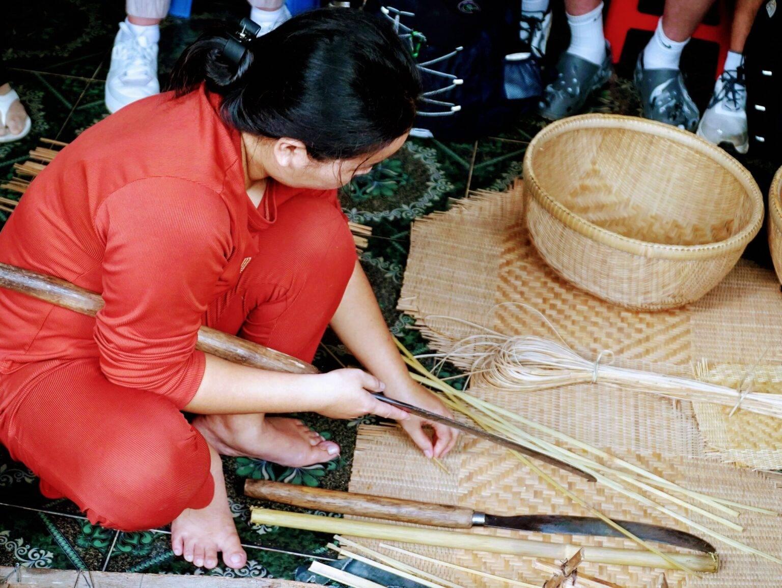 A woman weaving a bamboo basket.
