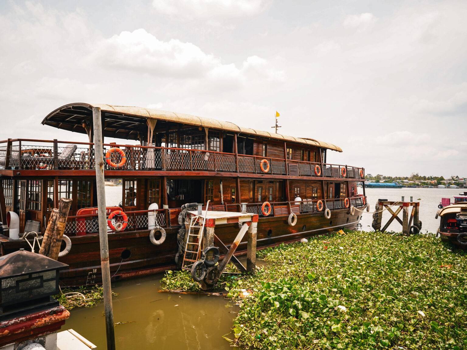 The Basaac 2, a large wooden river cruise ship on the water.