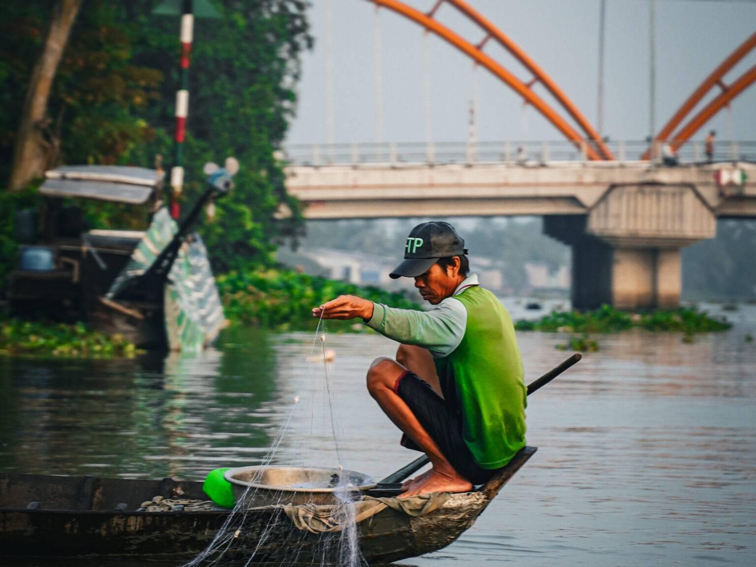 A fisherman sits in his boat and fishes.