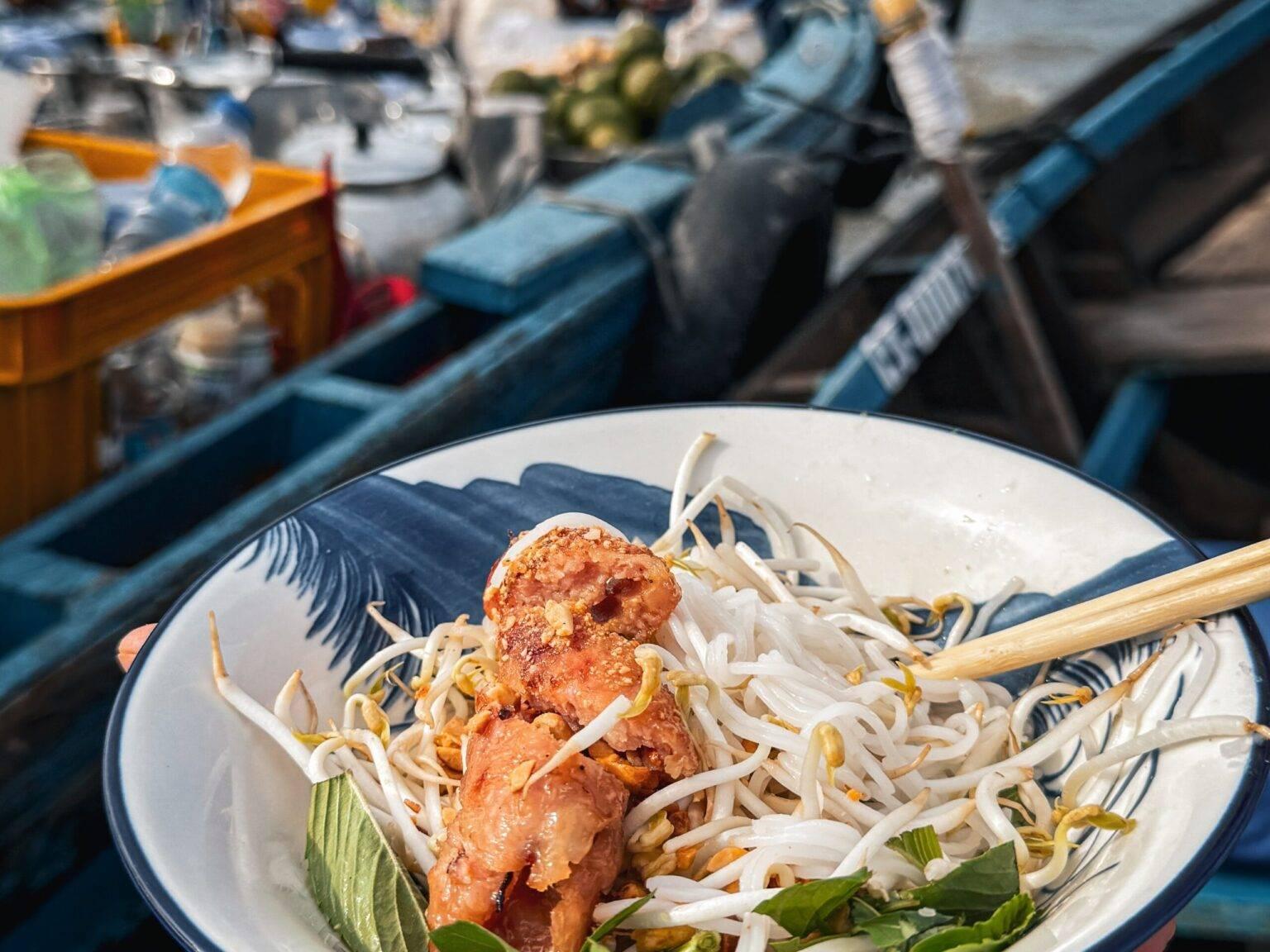 A bowl of food. In the background are boats on the water.