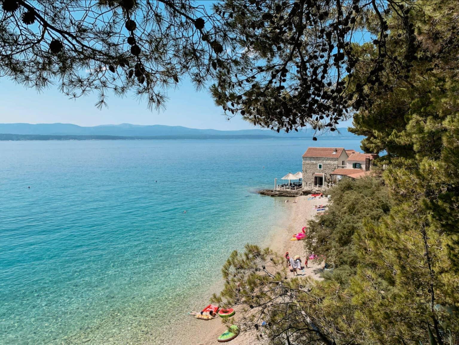 Aerial view of an inviting beach cove with sandy shores and turquoise water along the Adriatic coast of Croatia.