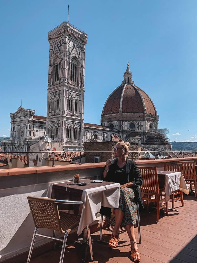 Consejos secretos de Florencia: Una mujer sentada en una terraza, una iglesia al fondo.