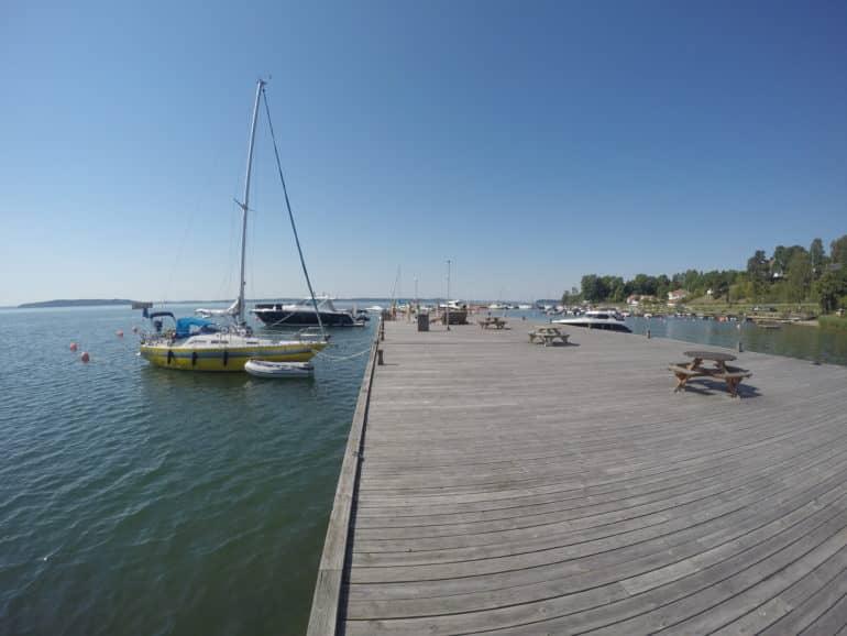 En un amplio embarcadero de madera junto al mar de Bråviken, un par de barcos están anclados.