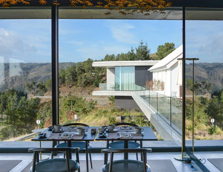 A modern house with a large dining area and large glass windows.