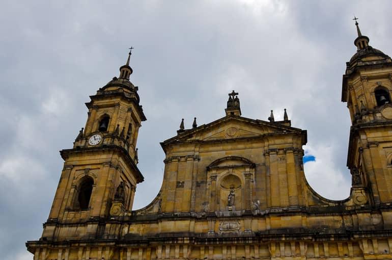 The old buildings at Bogotá's Plaza de Bolívar are painted yellow with two towers and have darkened edges over the years.
