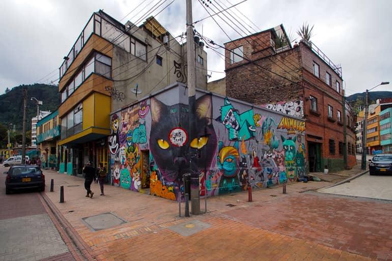 At a corner in Bogotá, Colombia, a streetlight has been integrated into the graffiti art, depicting a black cat's face.