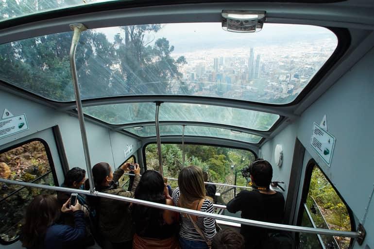 In a gondola on the way to Monserrate Mountain in Colombia, tourists photograph the view of Bogotá.