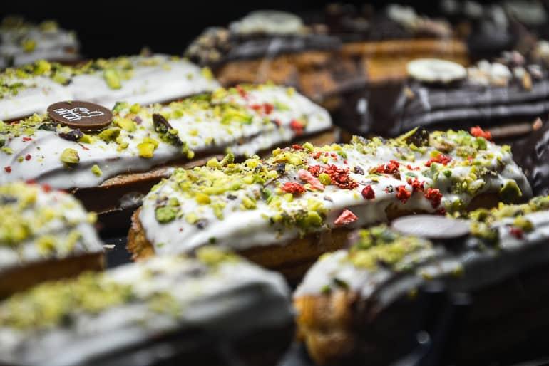 Los deliciosos eclairs en la cafetería Fat Cat Eklērnīca en Riga están decorados con chocolate blanco, lavanda, almendras tostadas o pistachos.