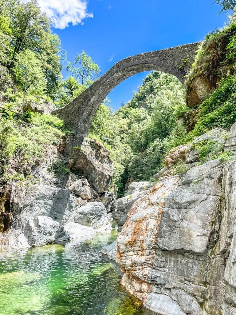 The clear water flows under the Roman bridge in Centovalli.