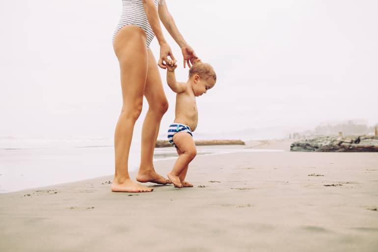 Parental Leave Travel: Baby learning to walk on the sandy beach