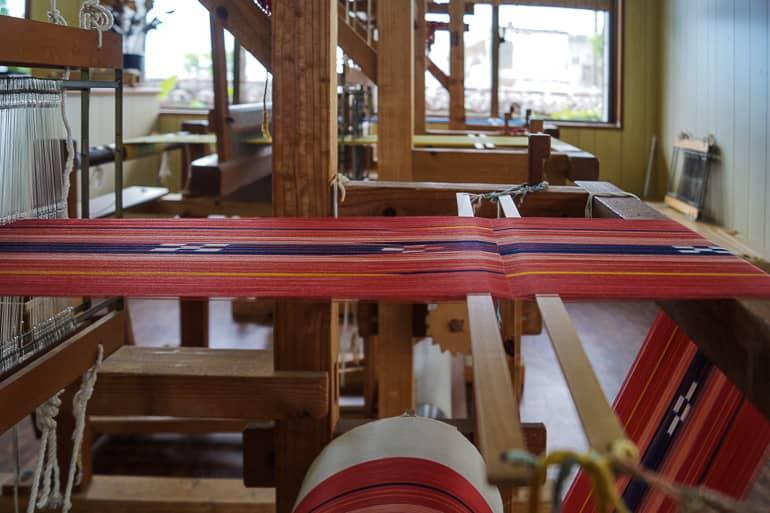 Colorful fabrics run through the wooden loom structure of the Minsa Weaving Studio on Ishigaki, Yaeyama Islands in Japan.