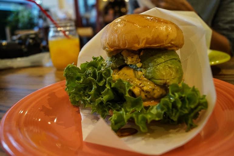 On the Yaeyama island of Ishigaki in Japan, a burger from Ishigaki Village is served on an orange plate wrapped in paper.