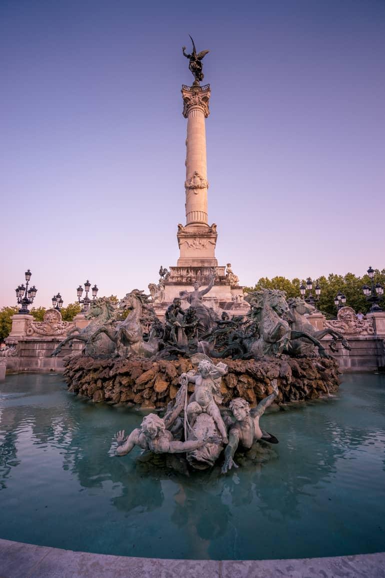 City trip: A fountain with a small tower in the middle surrounded by sculptures.