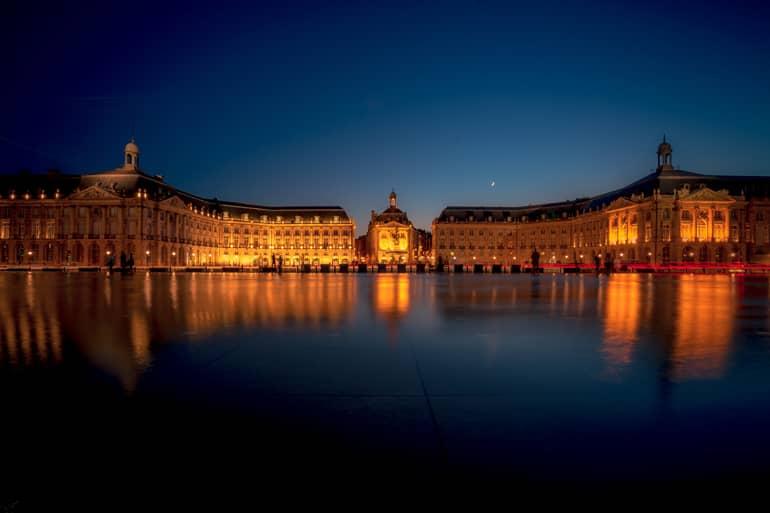 City trip: An old building in front of a pond at night.