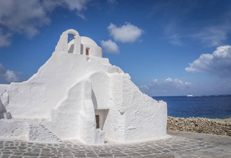 Una iglesia blanca con el mar al fondo.