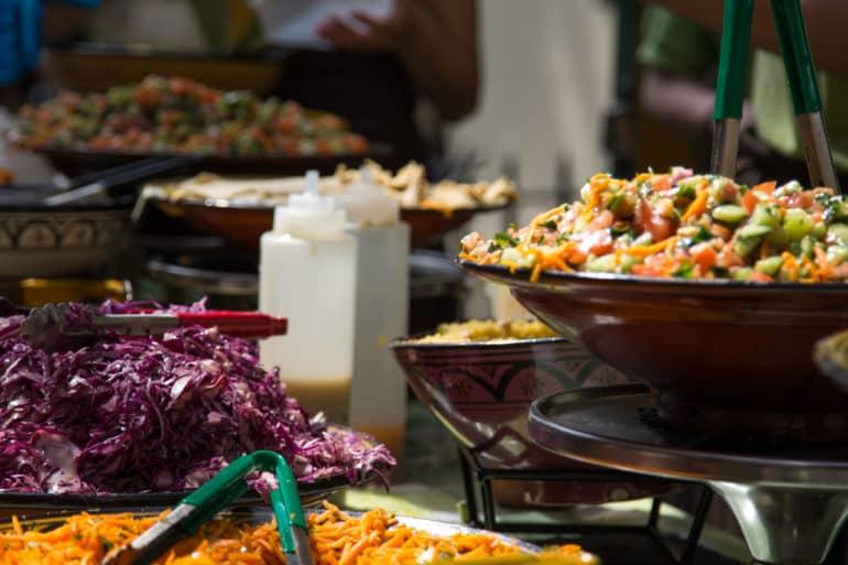 At Nicholas Market in Bristol, England, various salads are offered for sale in large dark bowls.