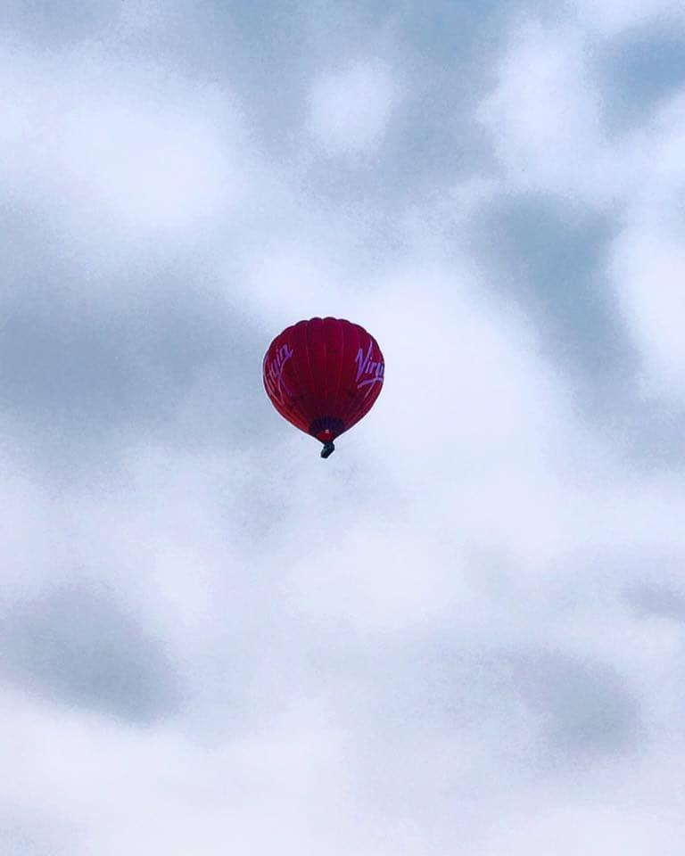 A red hot air balloon rises into the cloudy sky of Bristol, England, during the Balloon Fiesta.