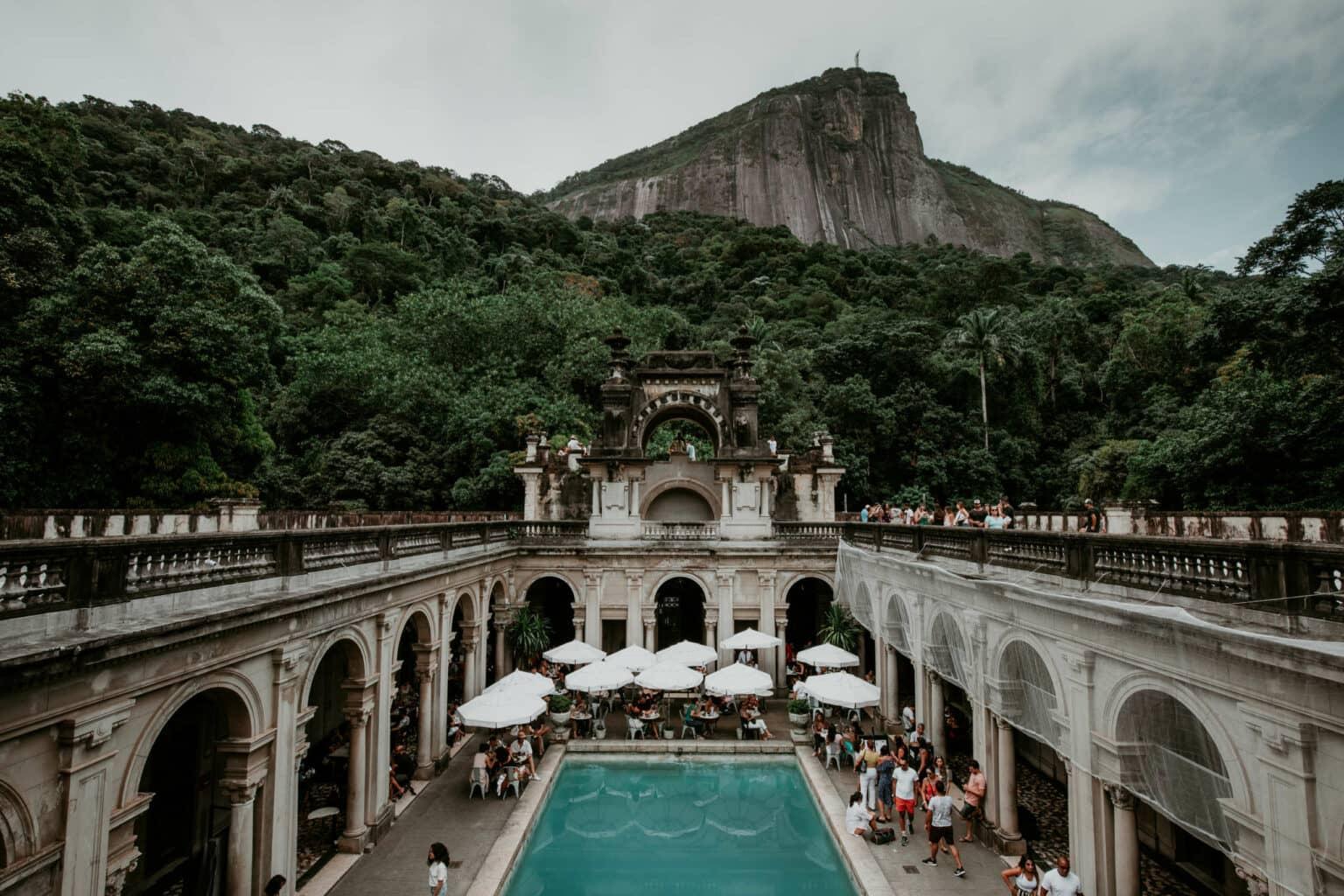 Una piscina con un café y una montaña al fondo.