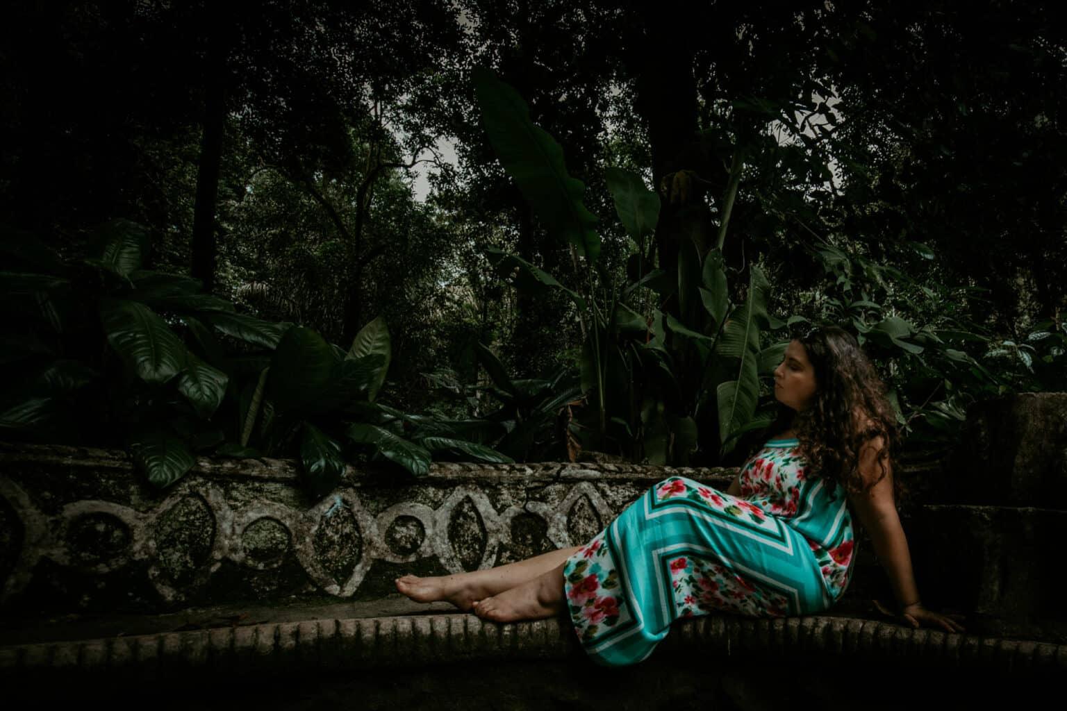 Una mujer sentada en un banco bajo los árboles.