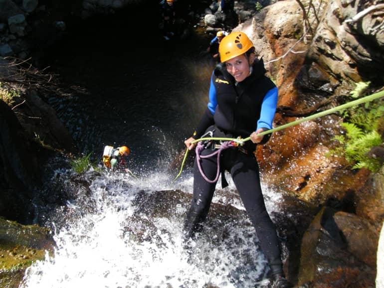 Madeira diving, surfing: A woman is belayed on a rock in the water.