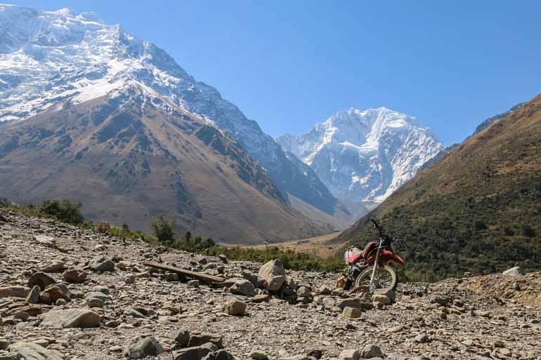 On the Salkantay Trek with a motorcycle standing on a gravel area in view of the Salkantay.