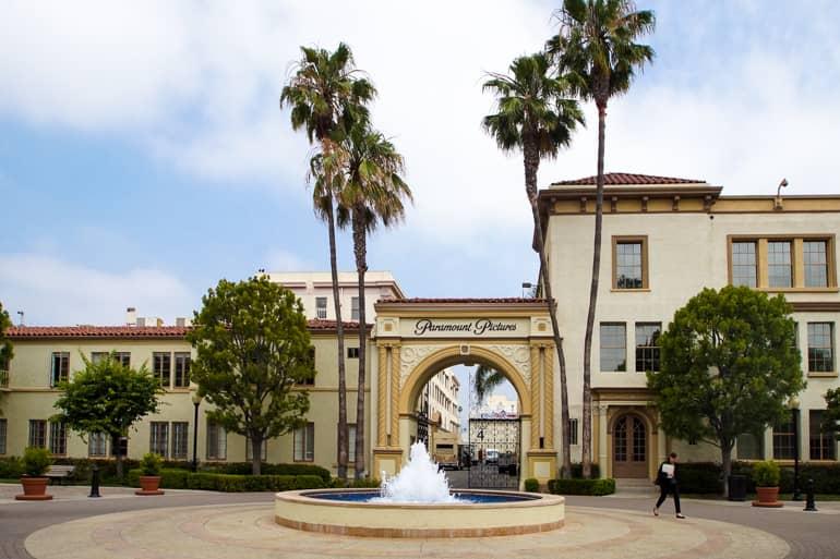 Delante de la puerta de entrada a los Paramount Studios en Los Ángeles hay una fuente y está rodeada de palmeras.
