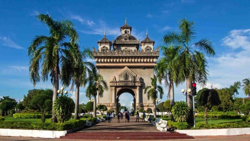 The Patuxai Arch, framed by palm trees, is located in Laos' capital Vientiane and is adorned with three decorative towers.