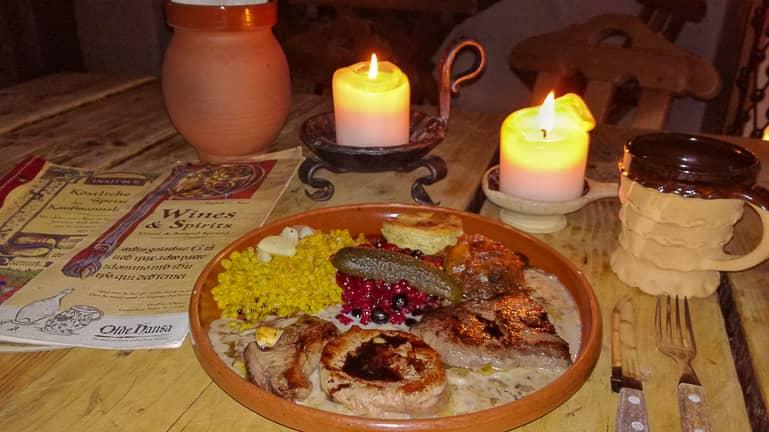 At Tallinn's restaurant F-hoone, a dish with venison fillet is served on a clay plate by candlelight and a clay mug.