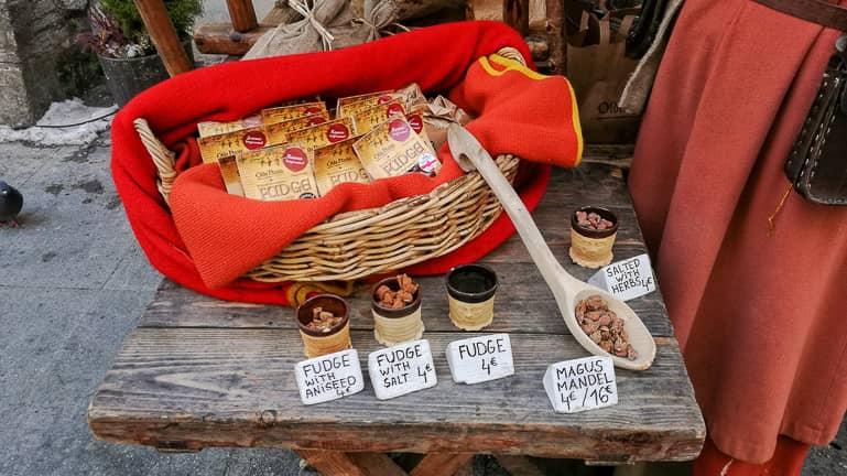 At a medieval-style market in Tallinn, caramel candies are arranged on an old wooden table in a basket for sale.