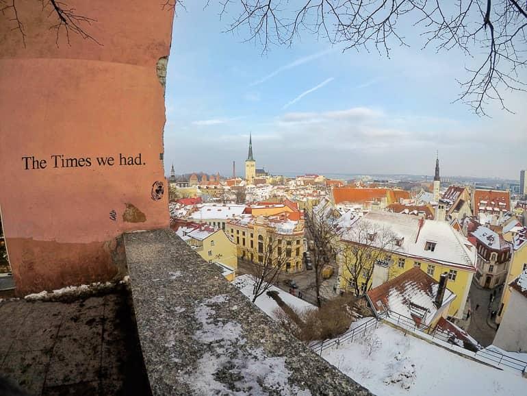 With a view of the city of Tallinn, the phrase: 'The time we had.' is written on an orange wall.