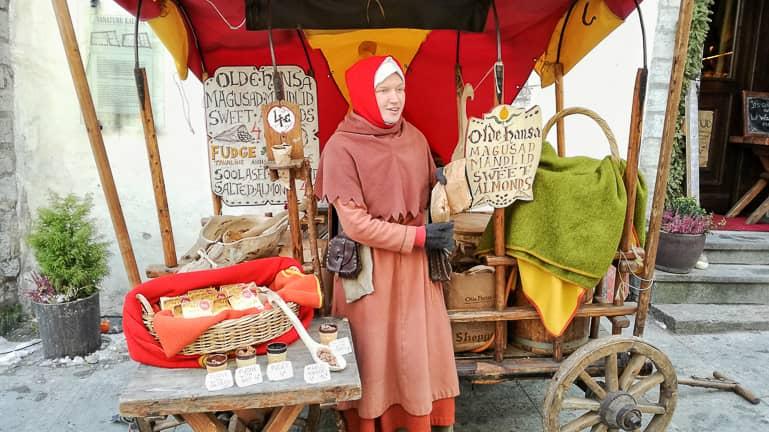 A woman in medieval clothing sells macaroon and almond products at her market stall in Tallinn.