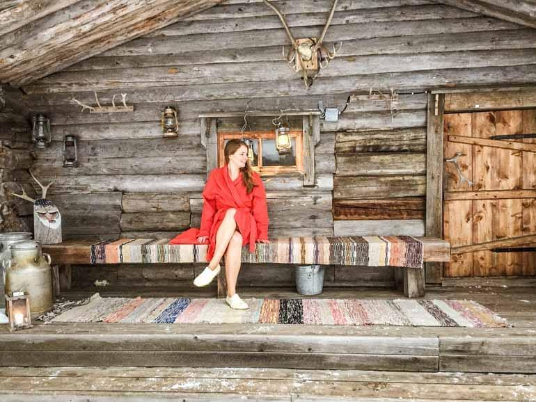 A woman sits in front of a sauna cabin in Finnish Lapland.