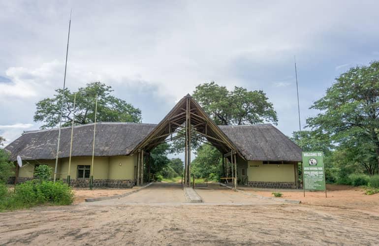 The entrance building of Chobe National Park with its wooden, light green shingle roof.