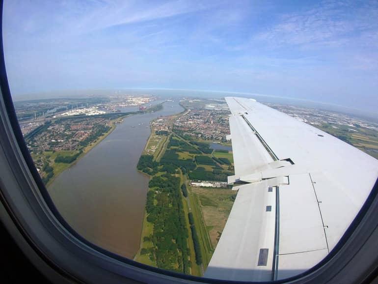 La vista desde la ventana del avión muestra un río que desemboca en el mar y el puerto de Róterdam.