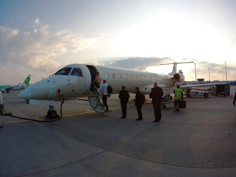 En el área de un aeropuerto, las personas suben a un avión durante el atardecer.