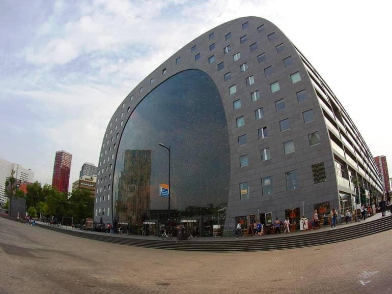 El edificio redondo del Mercado de Róterdam se destaca por su fachada de vidrio y las muchas ventanas cuadradas más pequeñas por encima.